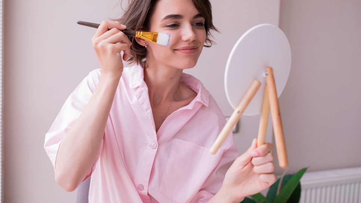 a woman in a pink shirt holding a brush and a mirror